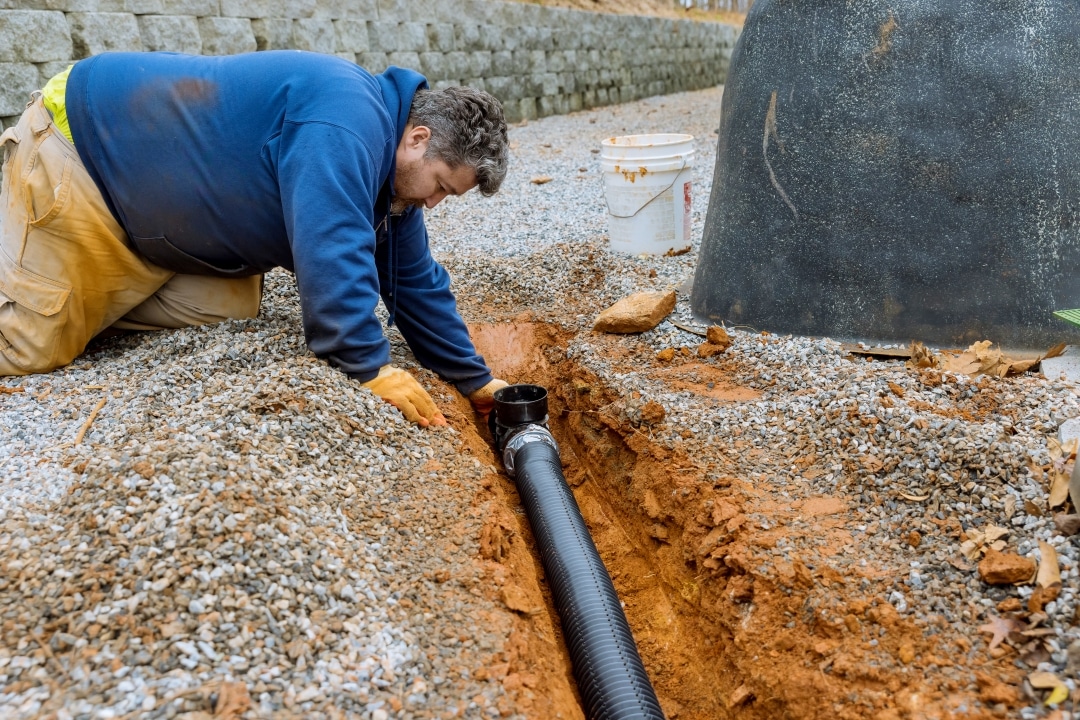 Man assembling drainage pipe for rainwater drainage | Salisbury Greenhouse - Sherwood Park, St. Albert